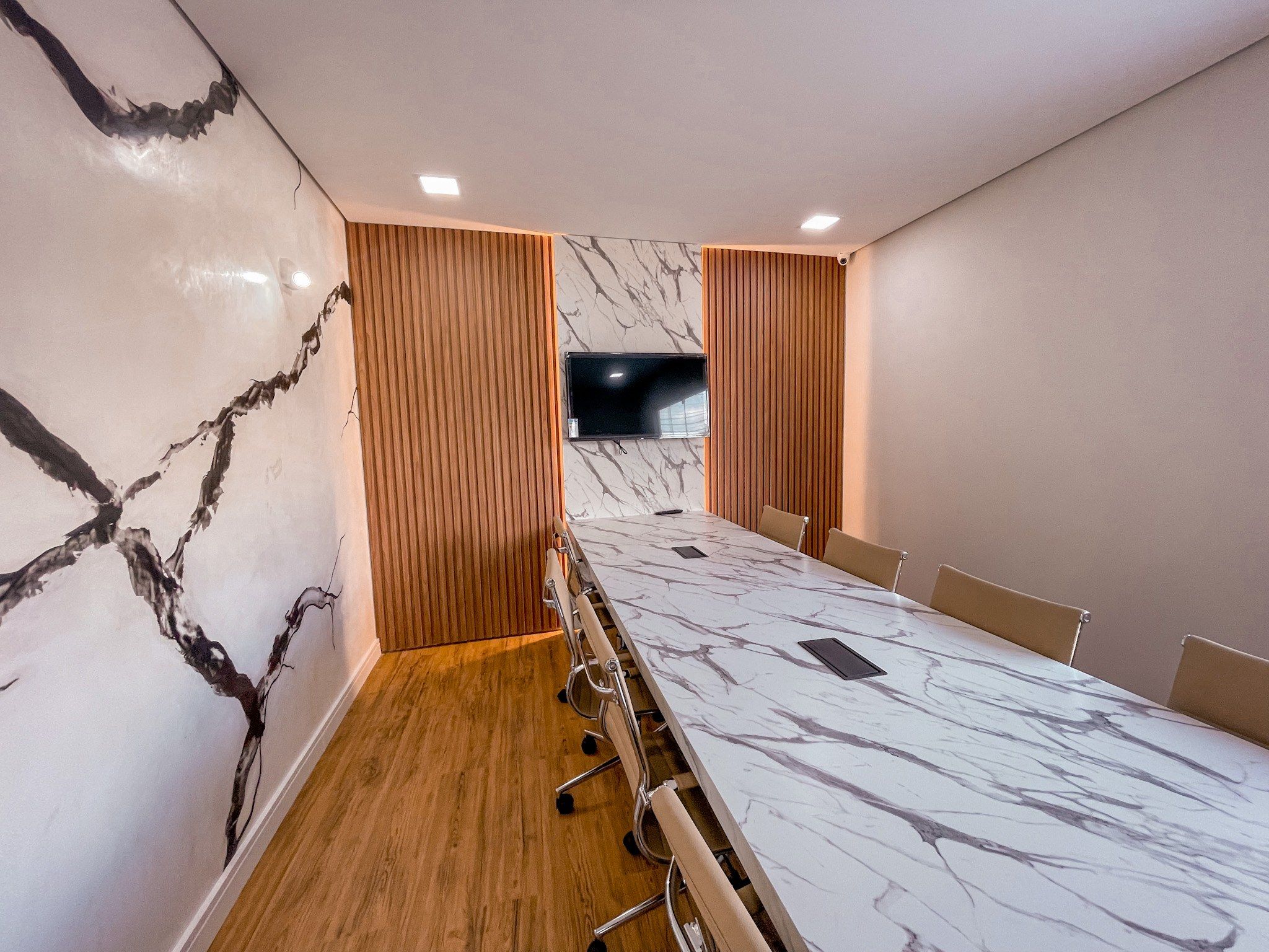 Sala de reunião com painel ripado e mesa em pedra — lojas e escritórios planejados pela Marcenaria Trevo em Belo Horizonte